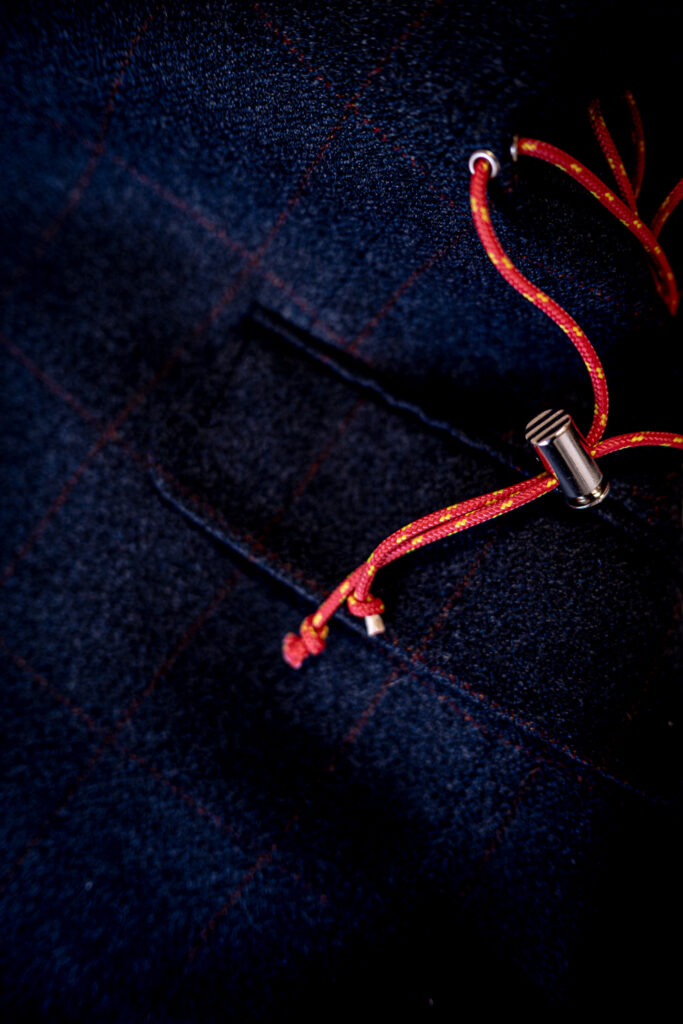 un dettaglio di un capo di abbigliamento che evidenzia un laccio dai colori caldi che spicca e si distingue sul tessuto blu